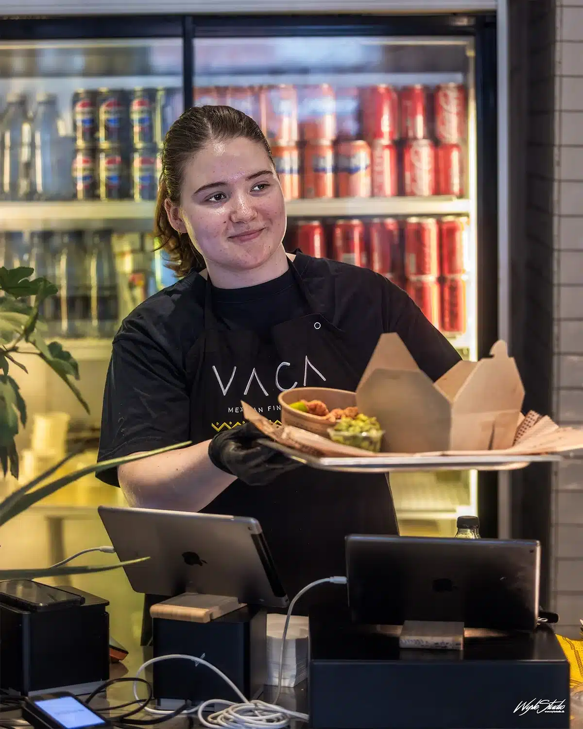 Smilende medarbejder serverer mad hos VACA