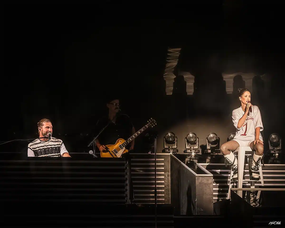 Lene Nystrøm sidder på barstol og synger, mens Søren Rasted spiller klaver under Aqua koncert i Tivoli Friheden.