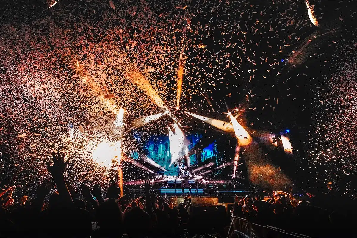 Publikum i Tivoli Friheden under Aqua koncert, hvor konfetti eksploderer over scenen i et festligt klimaks.