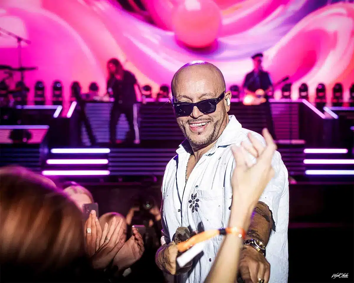 René Dif smilende blandt publikum i Tivoli Friheden, rækker hånden ud til fans foran den farverige Aqua scene.