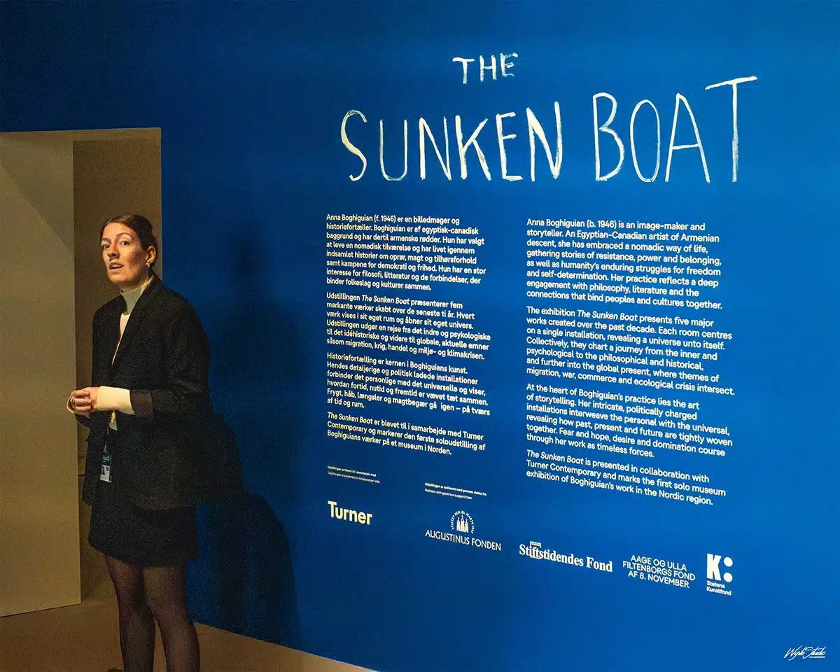 Kurator står foran den blå væg med titelteksten The Sunken Boat på ARoS under Anna Boghiguians udstilling.