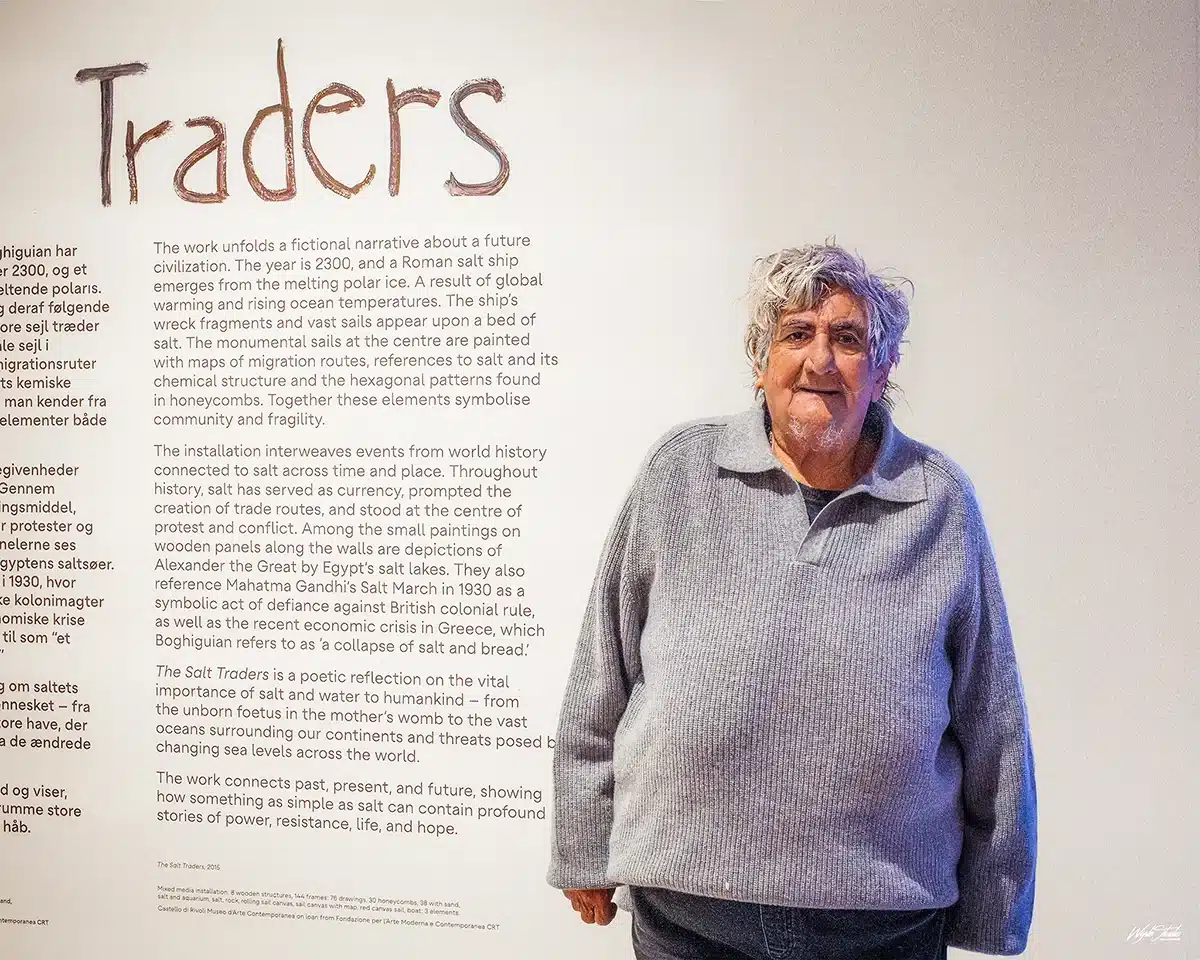 Portræt af kunstneren Anna Boghiguian stående foran tekstvæggen i værket The Salt Traders på ARoS