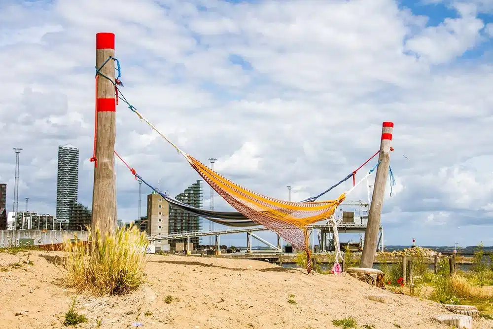 Store hængekøjer hænger mellem robuste træpæle i sandet på Pier 2