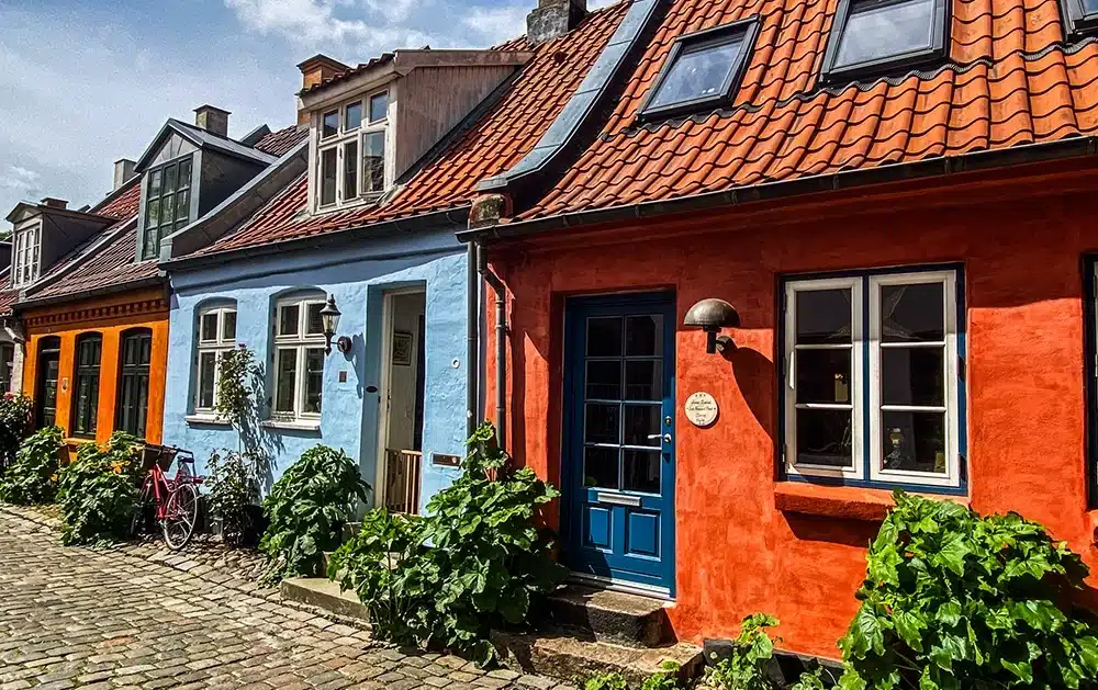 Blå og orange huse med grønne planter på Møllestien