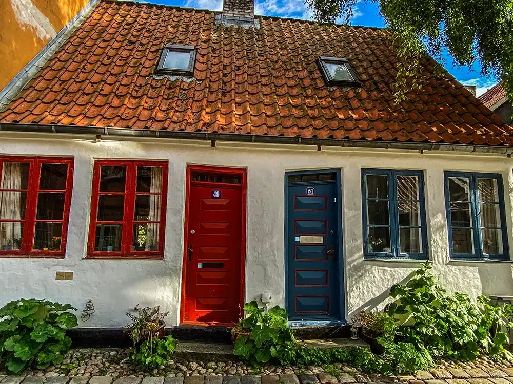 Et hvidt bindingsværkshus på Møllestien med røde og blå døre