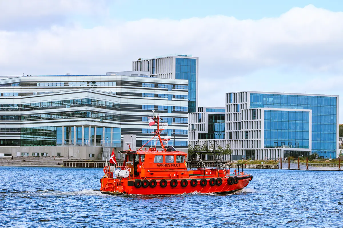 Lodsbåd sejler forbi Mellemarmen havn med bybaggrund