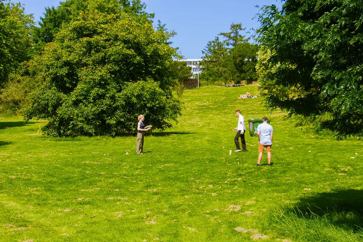 Venner spiller spil på plæne i botanisk have