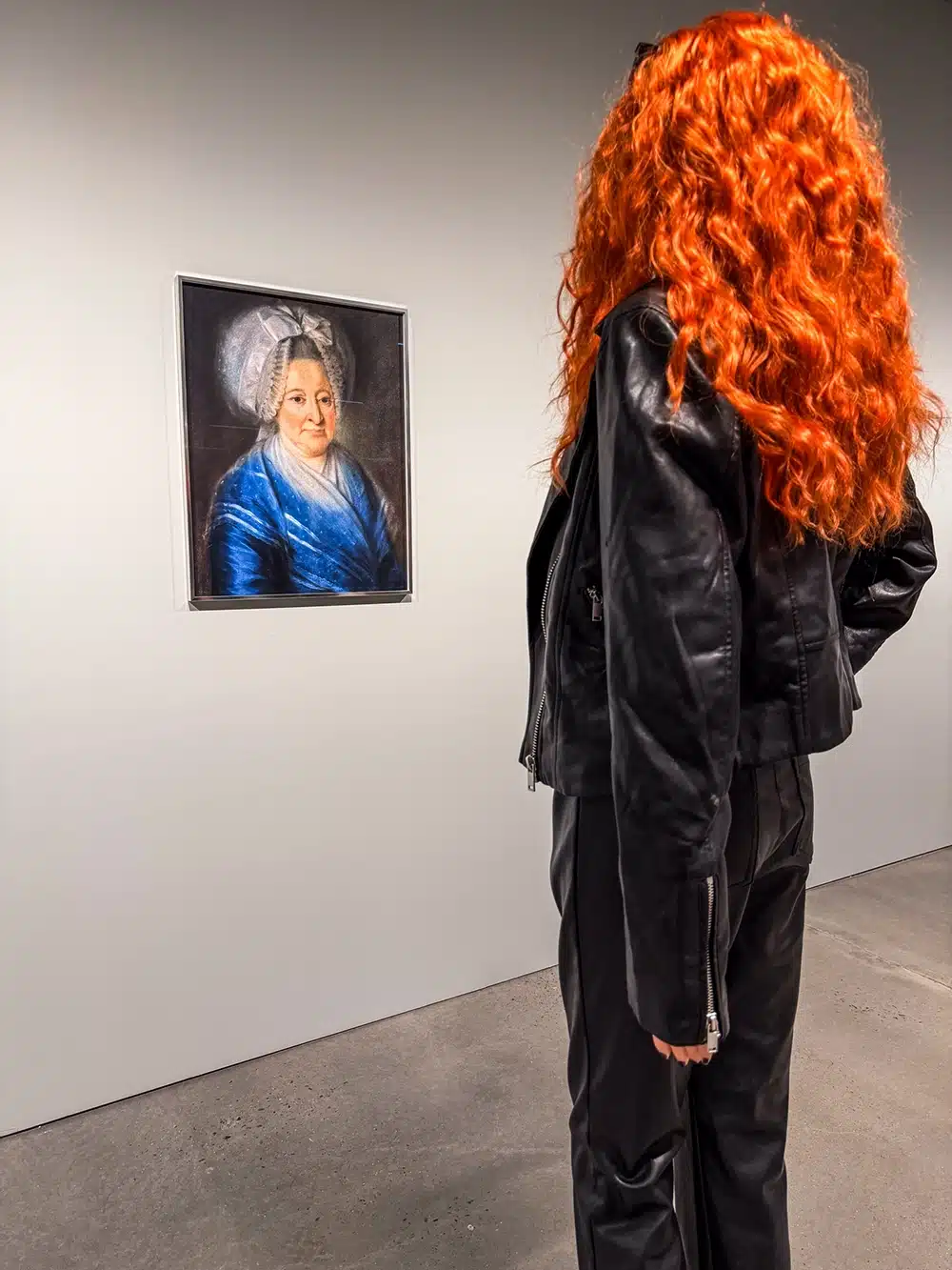 Mannequin rødt krøllet hår betragter portræt af kvinde i blå kjole på udstillingen The Populace på ARoS