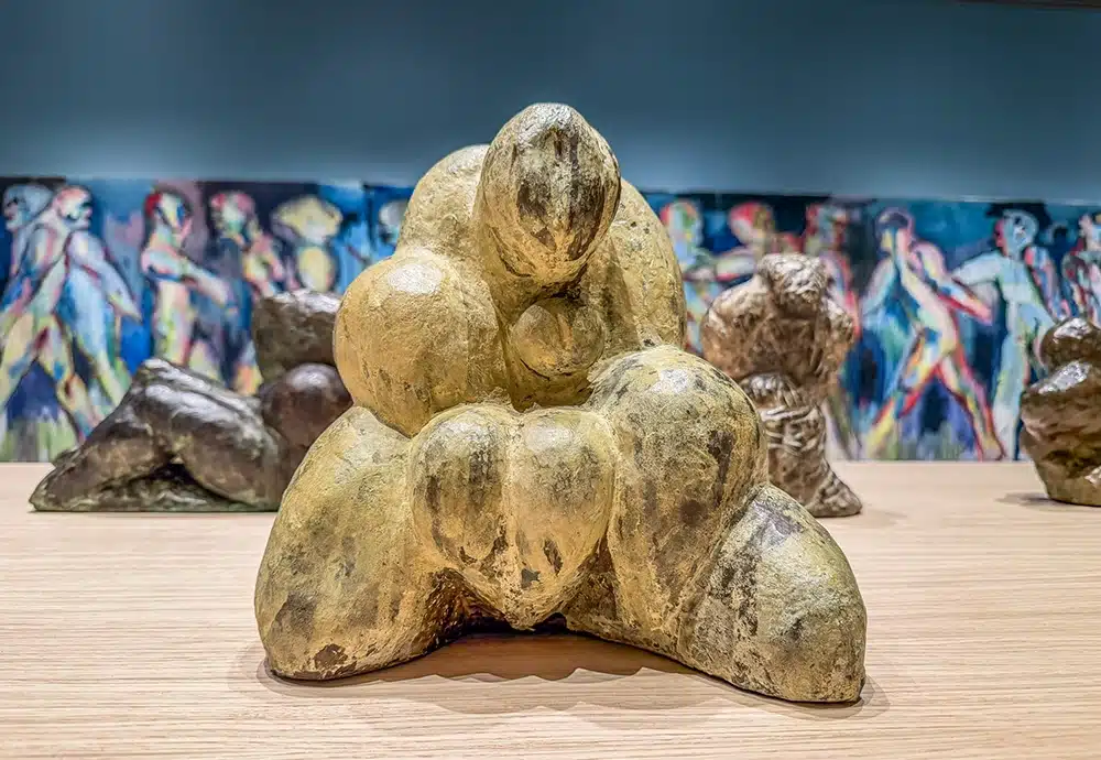 Sculpture of a curled up human body in front of a blue wall, Svend Wiig Hansen at ARoS
