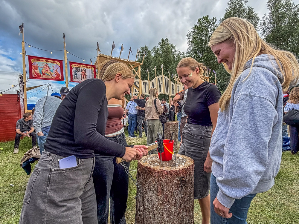 Tre festivalgæster prøver kræfter med søm i træstub i NorthSide 2026 Sideshow