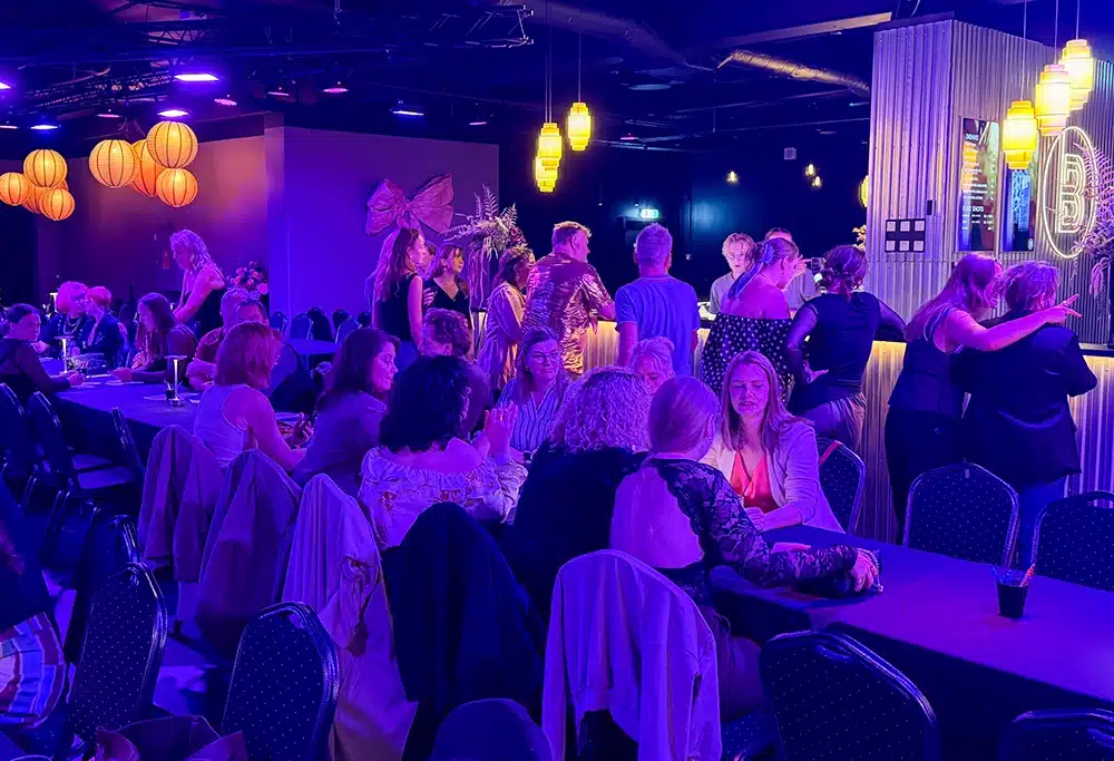 Fyldt lokale med gæster ved langborde i The Ballroom